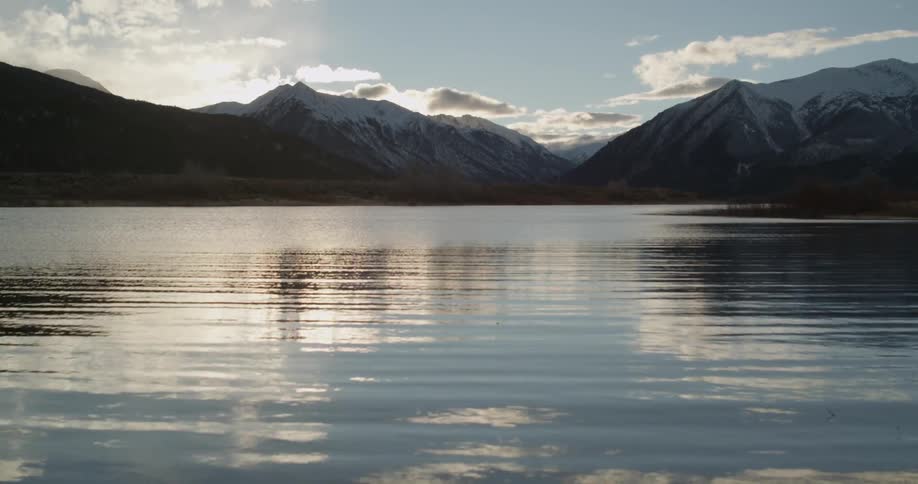 A snow capped mountain as seen from a river valley