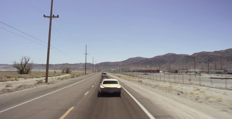 Vehicles driving on a flat highway with mountains to their right