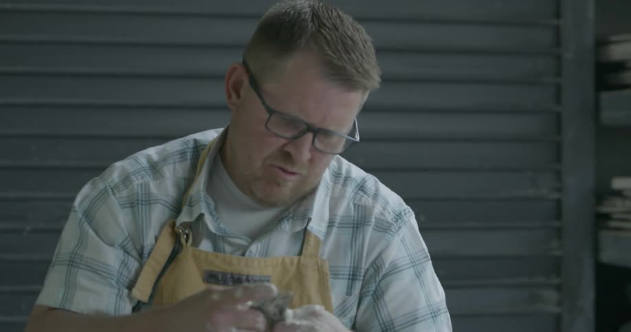 A man is shaping clay with his hands making a flower pot