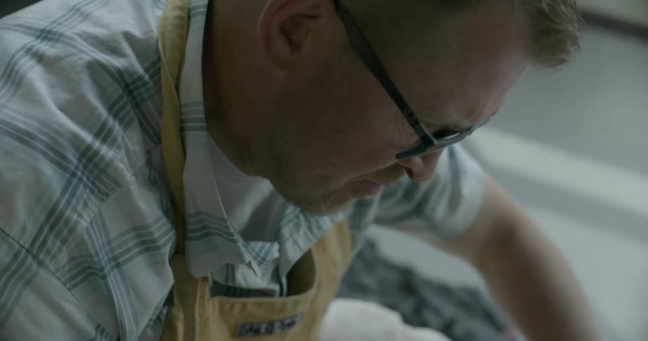 A man is working in clay on a pottery wheel