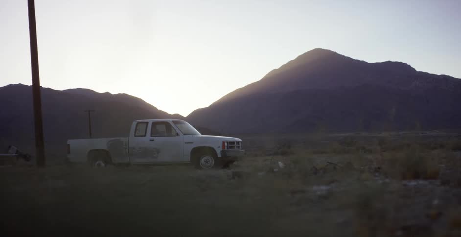 A truck is sitting in the middle of the desert at dusk