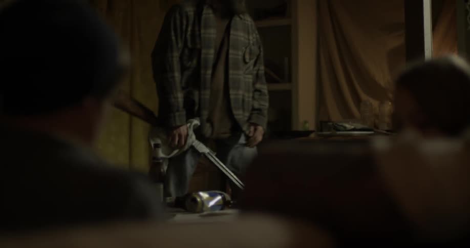 An older man holding a rifle stares as two teenagers as he gets up from his chair