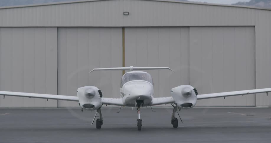 An airplane is taxiing away from a hangar during the day