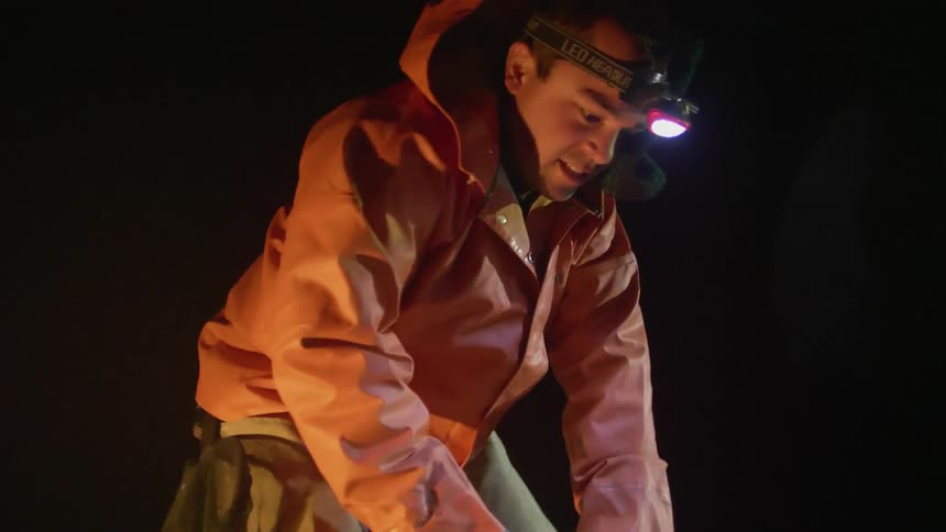 A man is working outside at night with a headlamp on