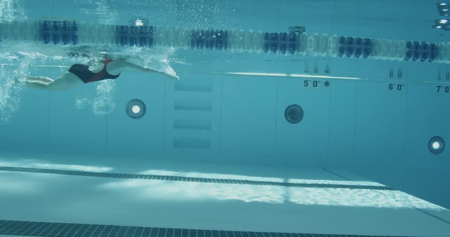 A woman is swimming fast in the pool kicking her legs behind