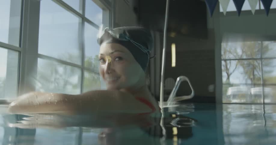 A woman is smiling as she rests in a pool during the day