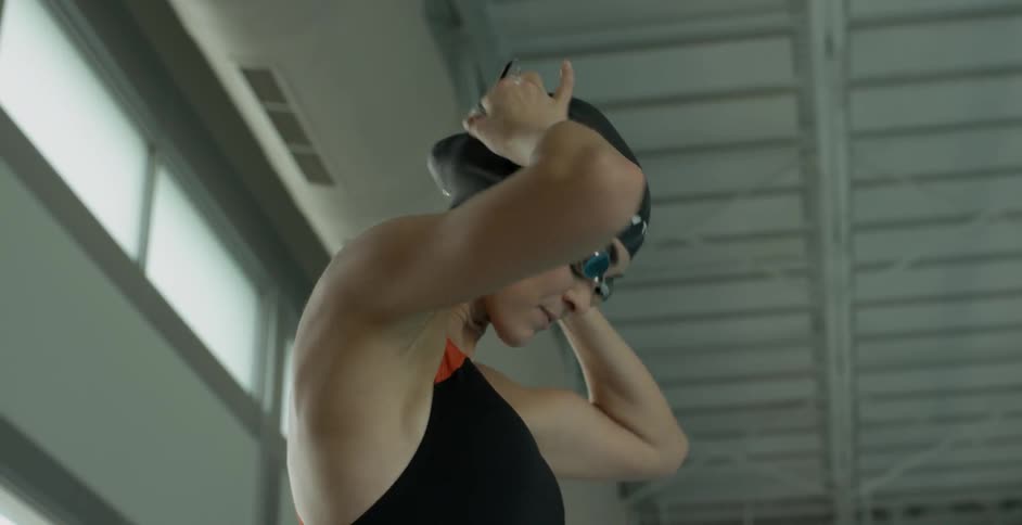 Woman puts on swimming goggles at indoor pool