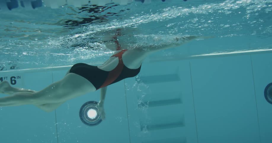 A woman is swimming laps at an indoor pool during the day