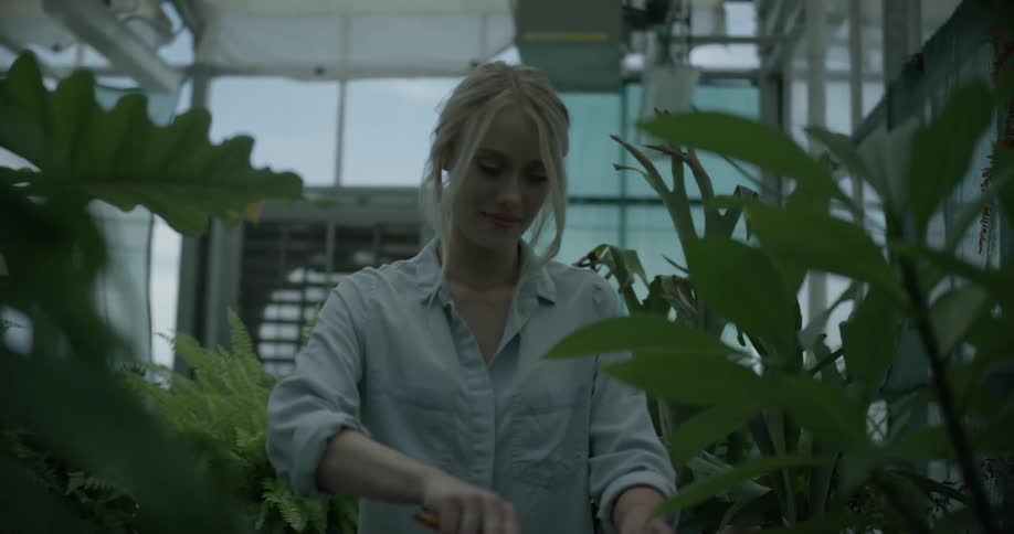 A woman is smiling while she is attending to her plants