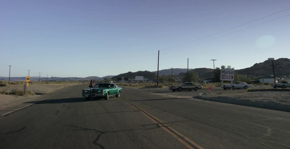 Cars driving down a road while a person stands in the middle of the road
