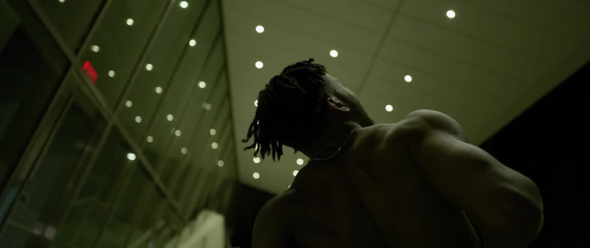 A man without a shirt is leaning back and stretching
