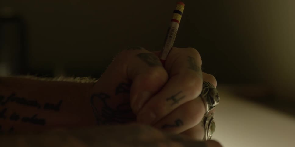 A person with tattooed hands is drawing something on a table