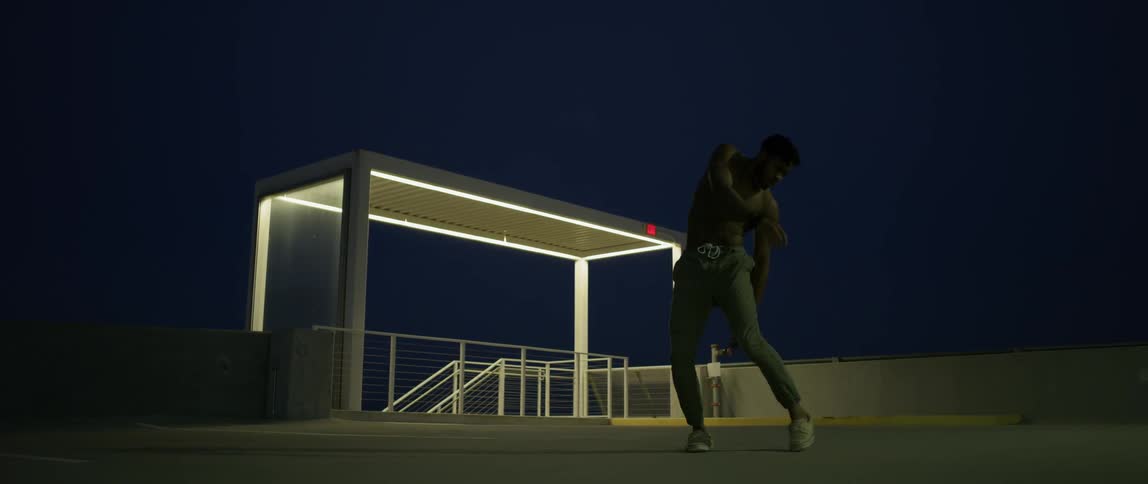 A man is dancing around on the roof at night