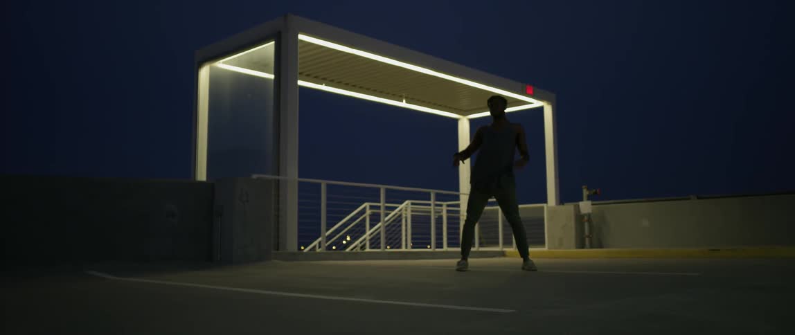 Person dances in a parking ramp at night