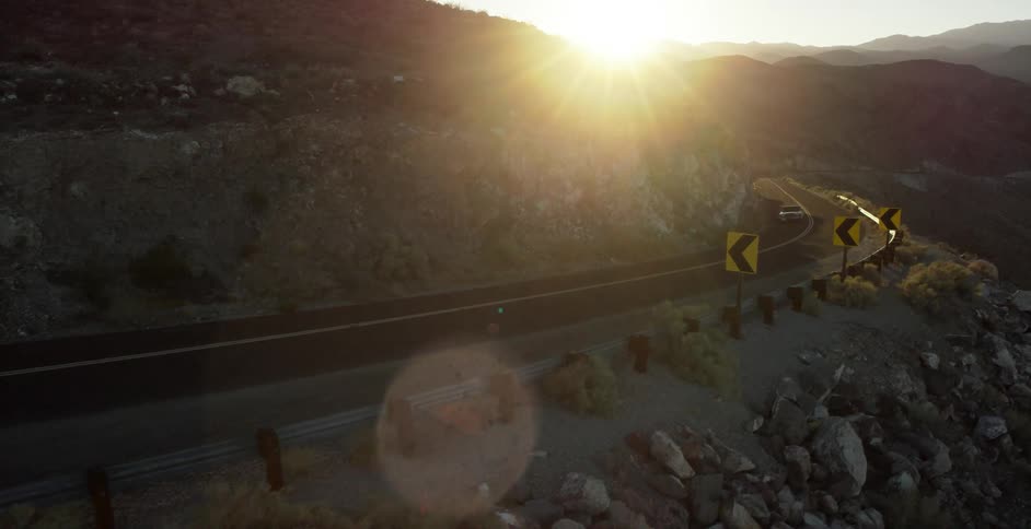 Car drives on a mountain road at sunset