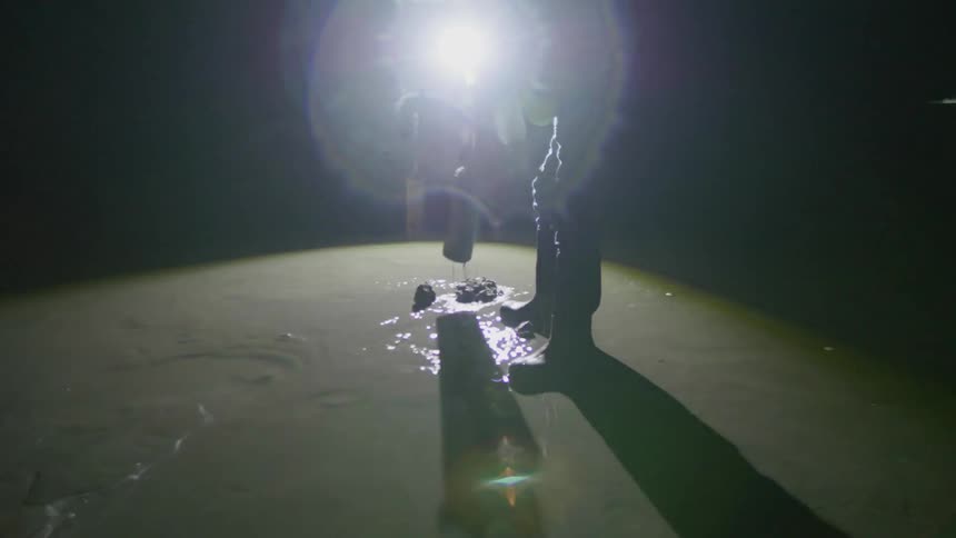A man is cutting large holes in the sand on a beach at night