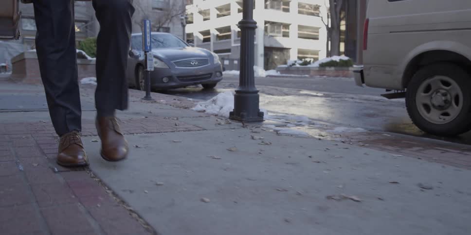 A man holding a briefcase walks down the road