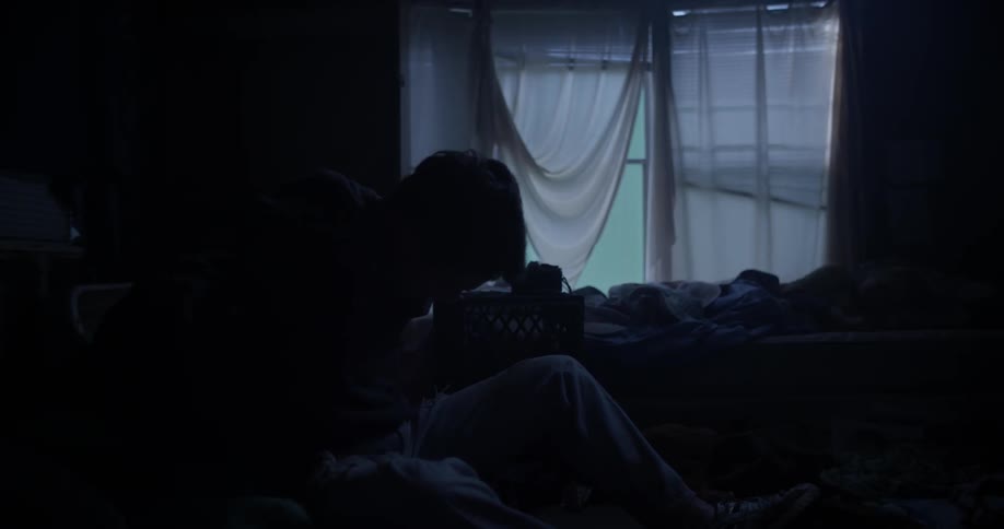 A man is getting dressed in the dark bedroom
