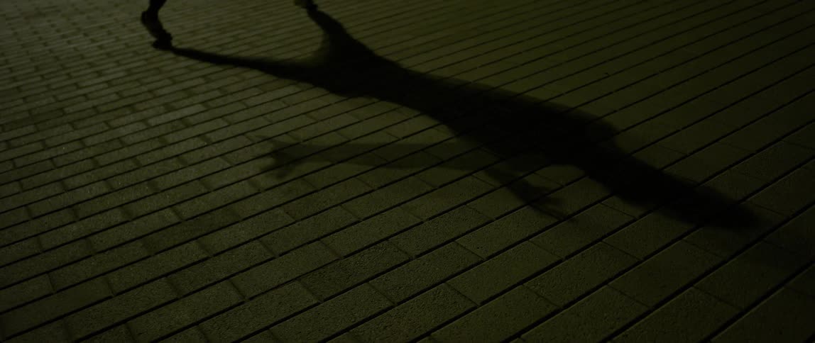 A man casts a shadow on the ground as he dances at dusk