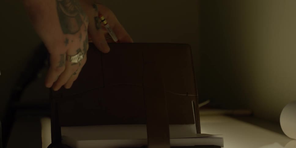 Someone with tattooed hands is going through a leather bound day planner