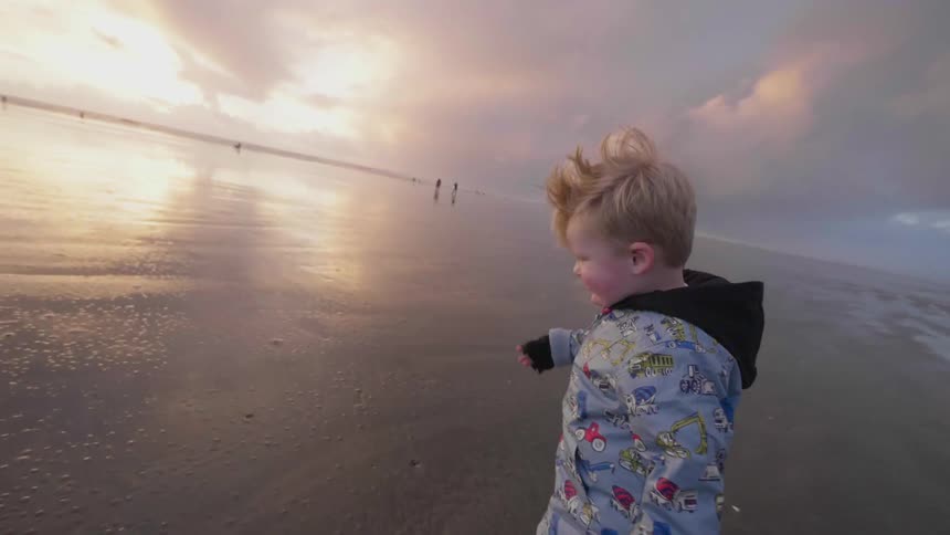 A child is running across the wet beach