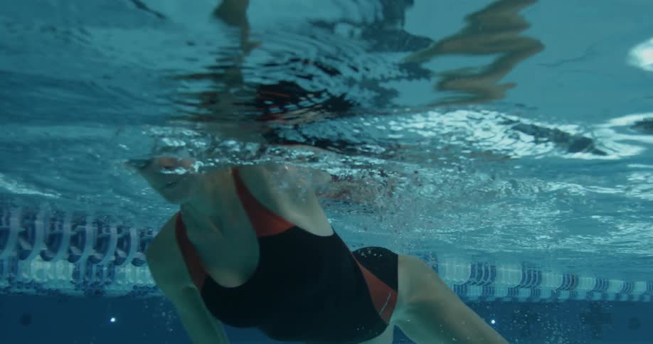 A woman is swimming underwater next to a camera
