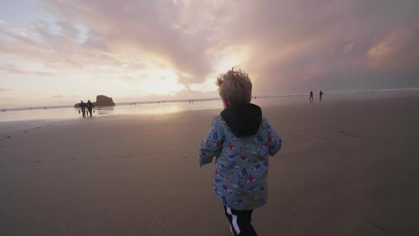A child is running towards people on the beach