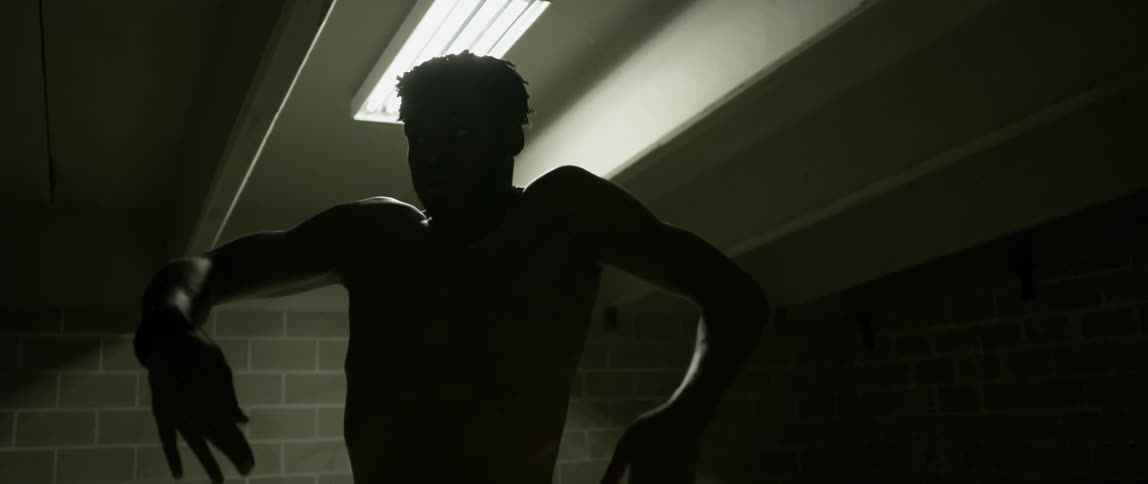 A man is rotating his shoulders as he dances in a brick building at night