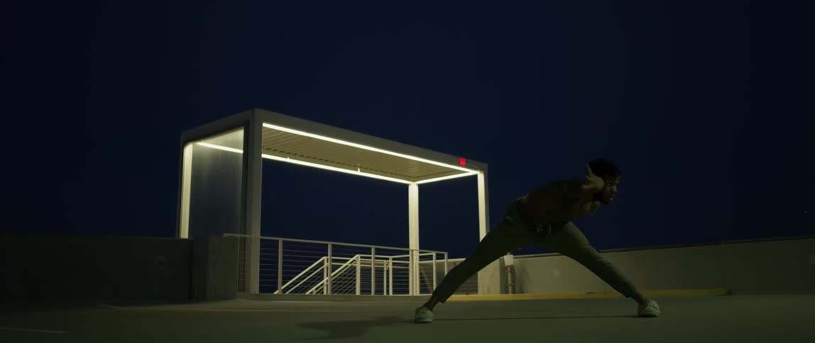 A man is dancing on a parking garage rooftop at night
