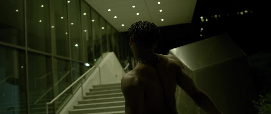 A man is dancing near a staircase in the city at night