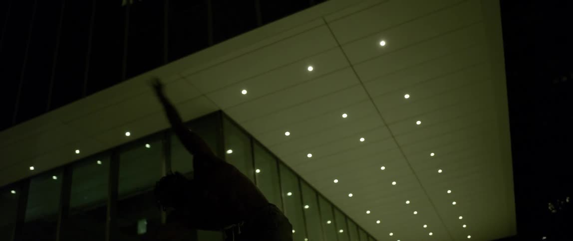 A man without a shirt is doing an interpretive dance at night