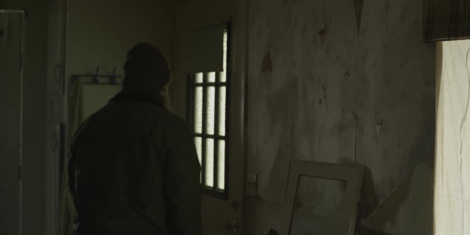 A man wearing a jacket exits a home during the day