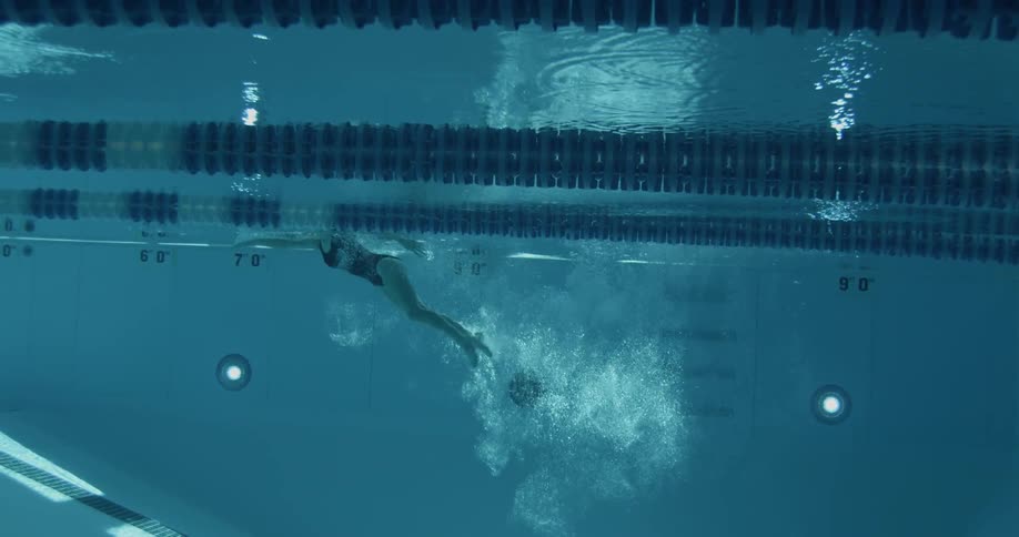 A woman dives into a deep pull and swims back towards the surface