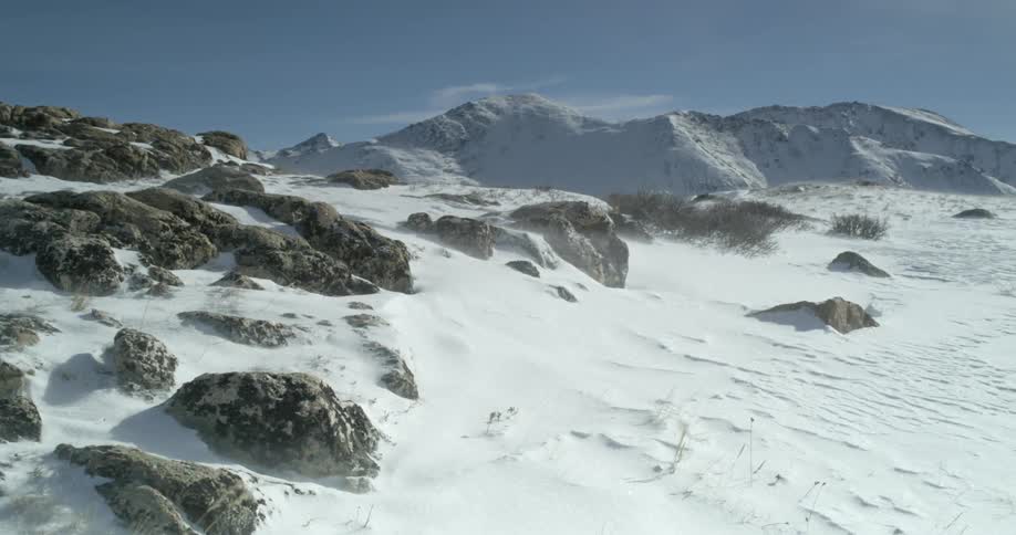 The wind blows snow on a mountaintop