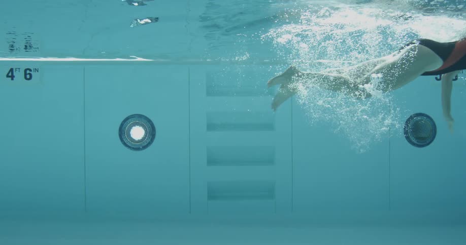 A woman in a pool begins to swim a lap