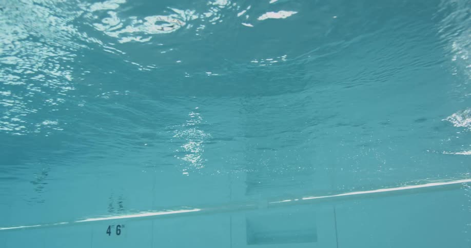 Woman swimming in a large pool as seen underwater
