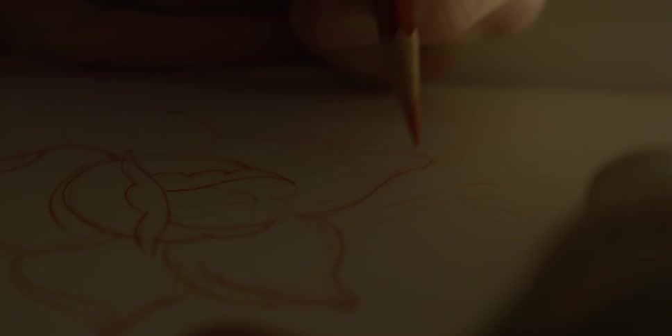 Someone is drawing a flower with a red pencil