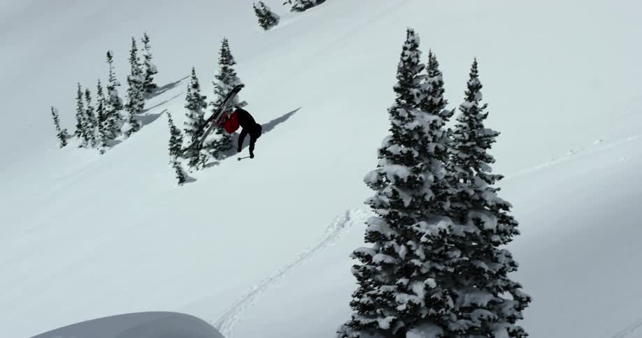 Person skiing soars through the air and lands on snow hill