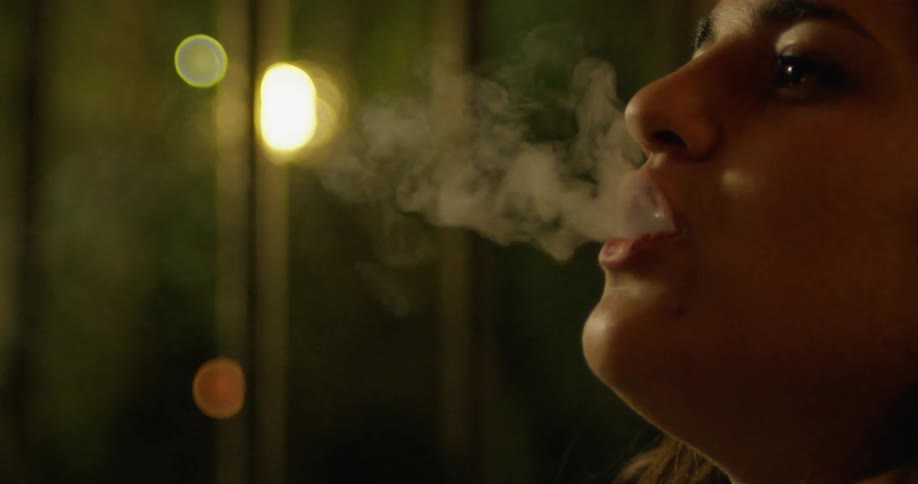 A woman takes a drag from a hookah