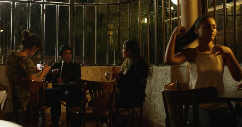 Woman smoke and socialize in a hookah bar at night
