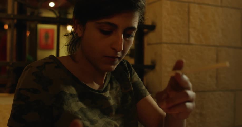 A woman is smoking and dunking a tea bag into water