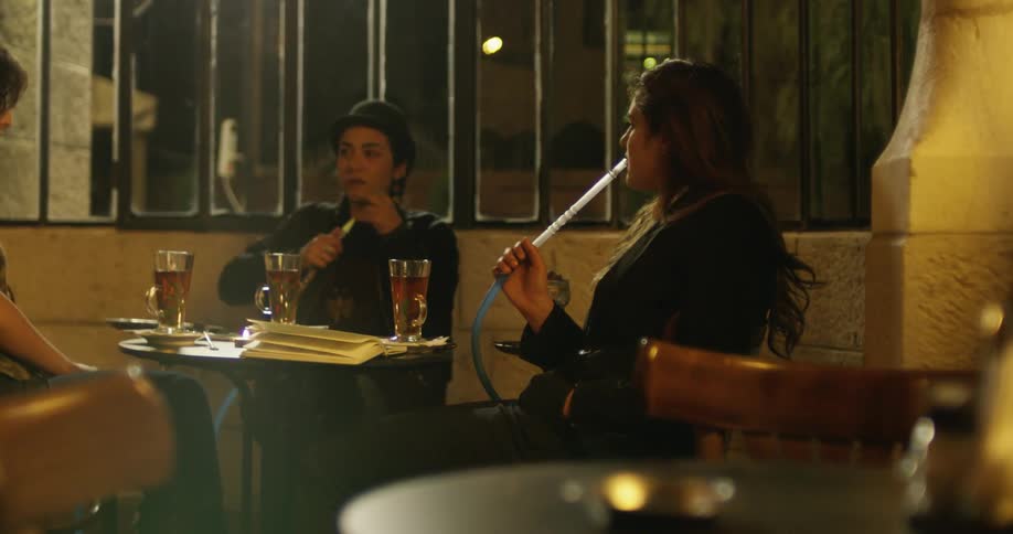 Three friends are sitting around smoking a hookah