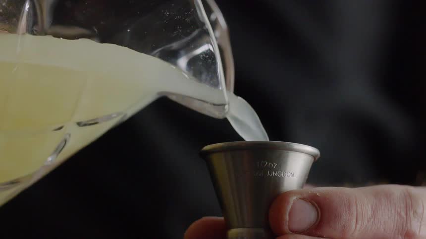 Someone pours lemonade into a small metal cup