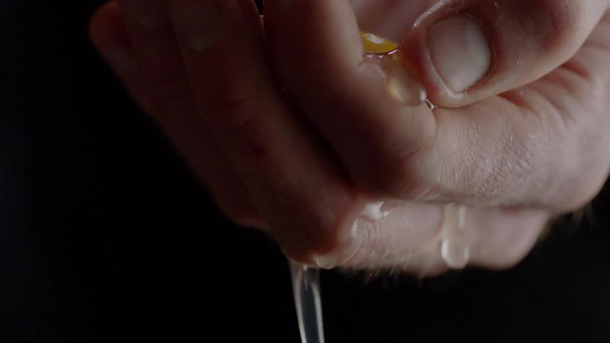 A person uses his hand to separate an egg