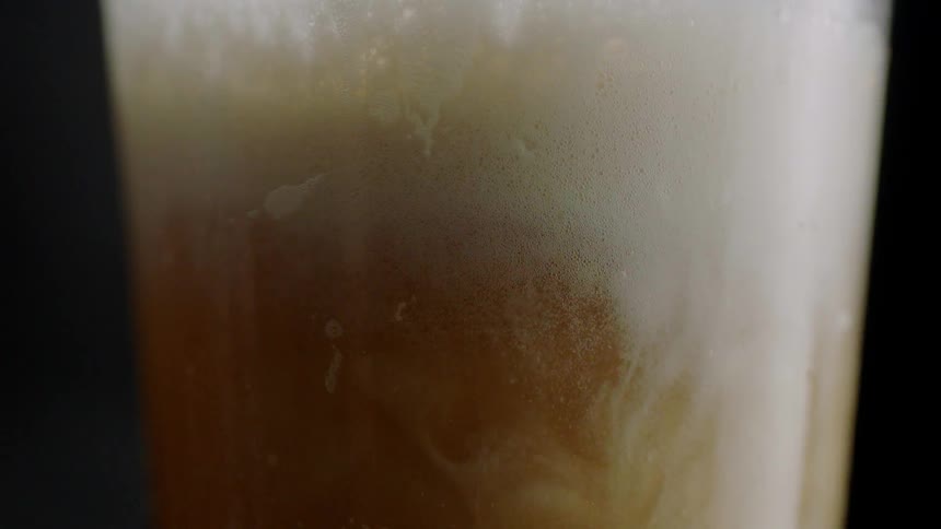 Foam swirls and builds in beer as it pours into a glass