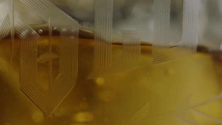 Liquid pouring into a glass with letters on the outside