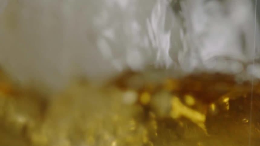 Liquor is poured over ice in a glass
