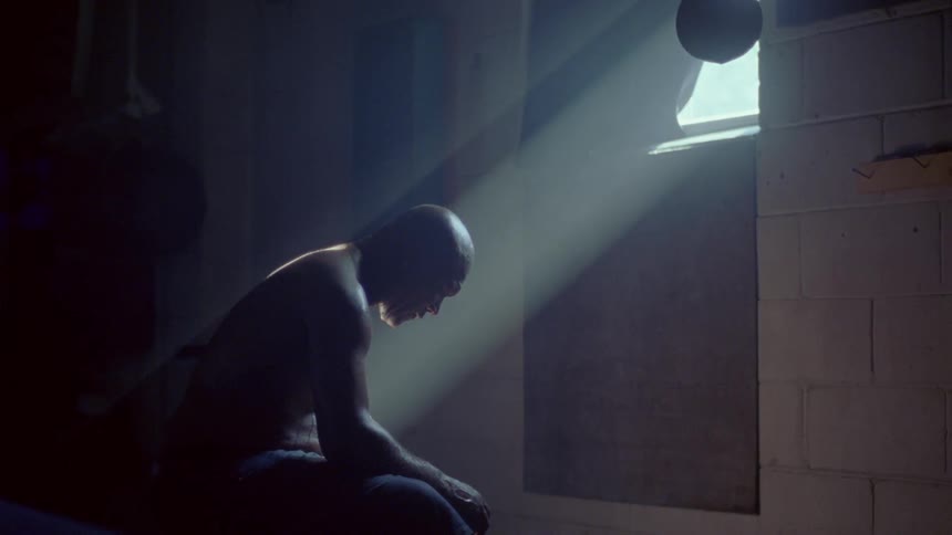 A man is sitting sweating in front of a window