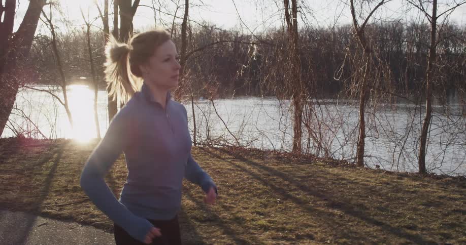 Woman jogging down a path by a lake