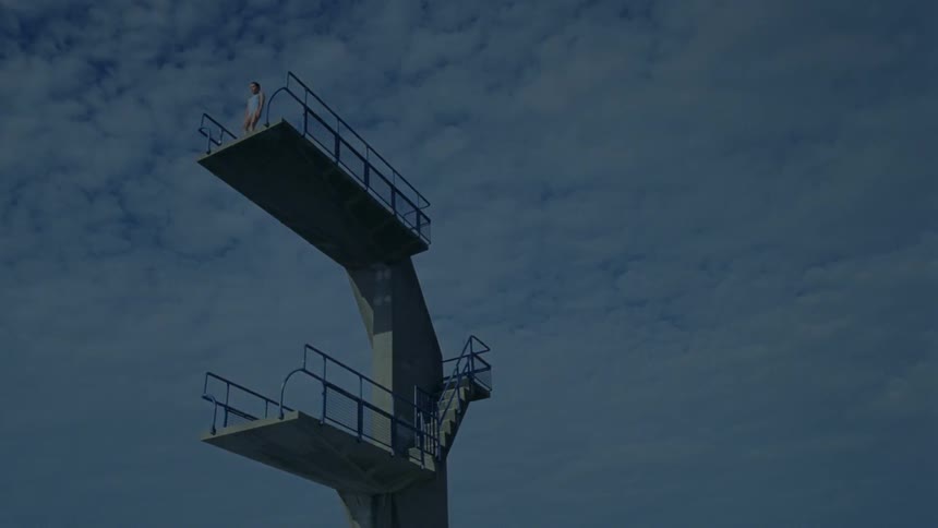 A woman jumps from a tall diving platform